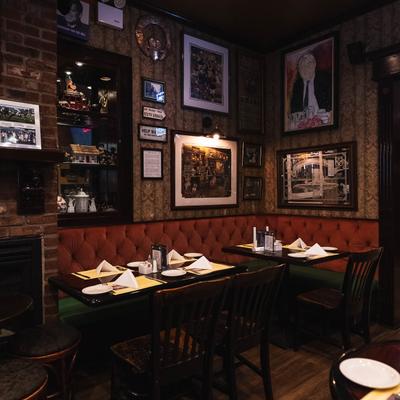 Pub interior with a red bench, set tables, and artwork on walls.