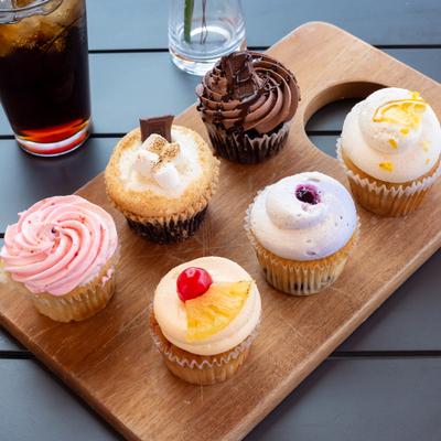 Different cupcakes served on a board, top view