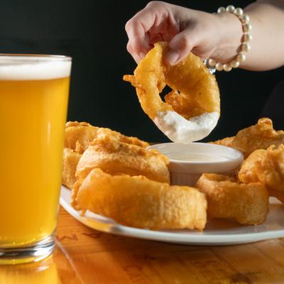 Customer dipping an onion ring into cream, closeup.