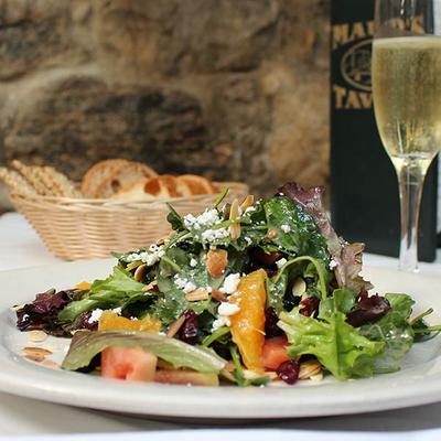 Mixed greens salad with orange slices, almonds, and cheese, served with sparkling wine.