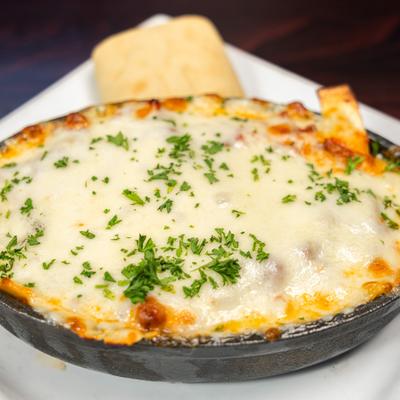 Lasagna skillet topped with melted cheese and fresh herbs.