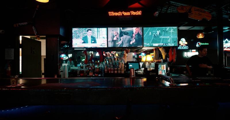 Dimly lit bar interior with TVs showing sports and news