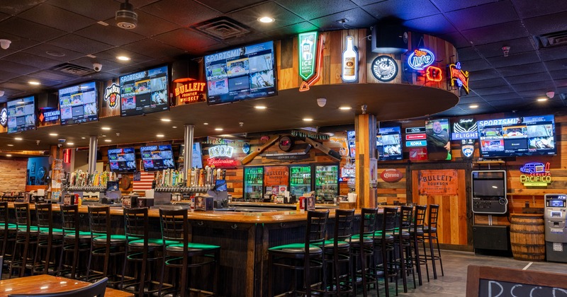 Interior, bar, chairs, screens above, drink rack behind