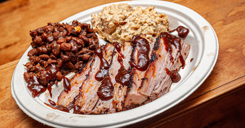 Sliced grilled meat, BBQ sauce, beans and dip