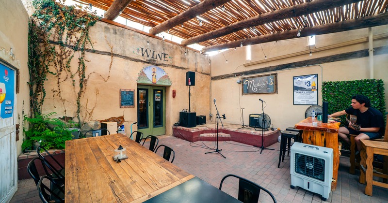 Rustic patio with a small stage and wooden tables