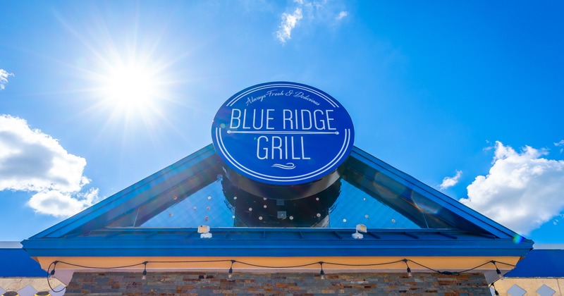 Exterior, blue-white sign on top of restaurant roof, blue sky behind