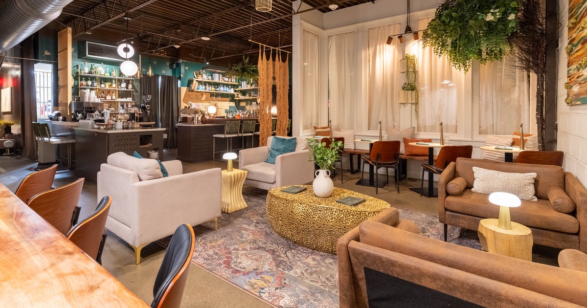 Interior, modern café with varied seating, a bar, plants, and contemporary decor