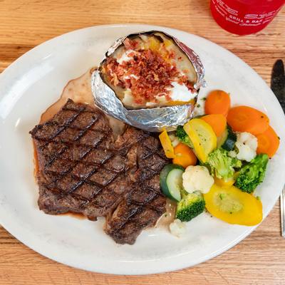 Rib Eye Steak served with potato skins and grilled vegetables.