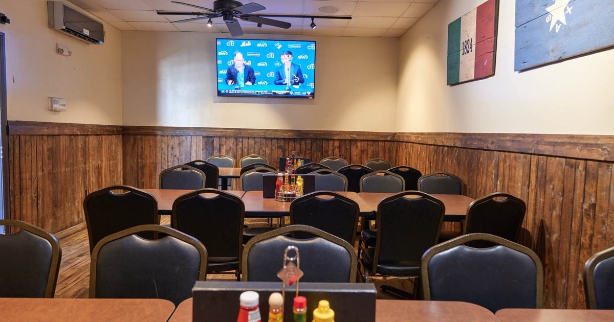 Tables and chairs set up facing a television mounted on the wall