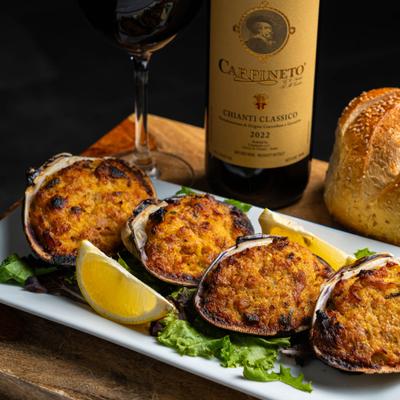 Baked stuffed clams served with lemon wedges and red wine.