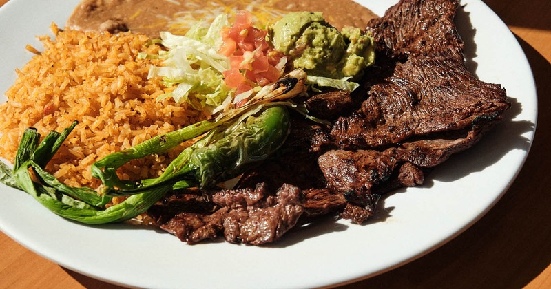 Grilled steak, with pico de gallo, salad, guacamole, rice, and beans