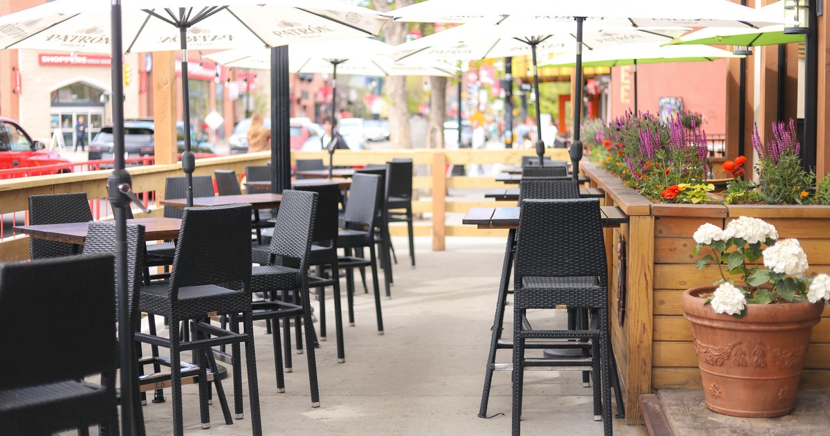 Exterior, patio, high wooden top tables with stools under parasols, restaurant front