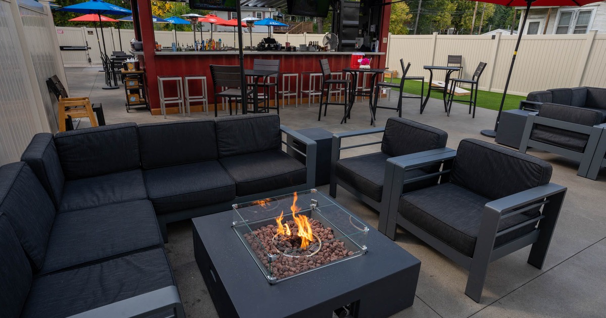 Exterior, outdoor lounge area, corner sofa with chairs and fire pit in the center