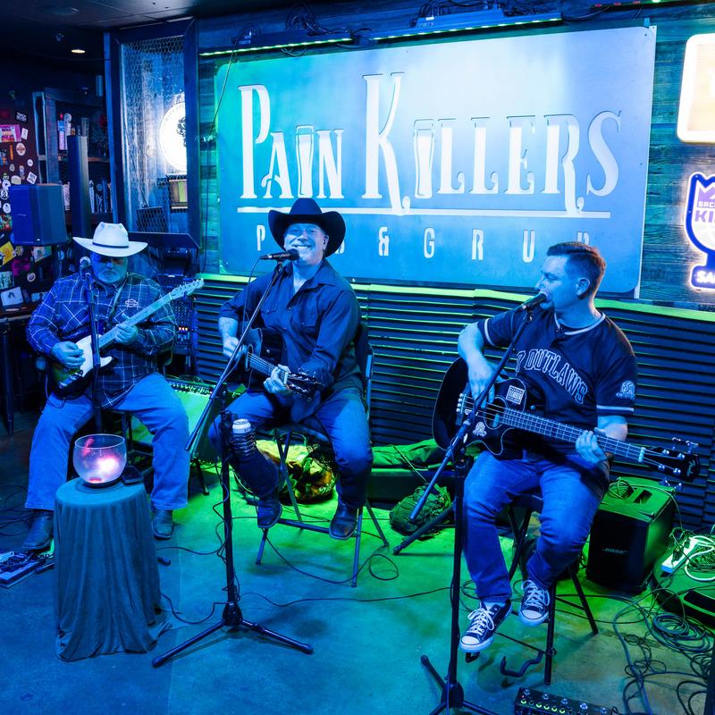 Band performing on the stage with pub's sign in the background.