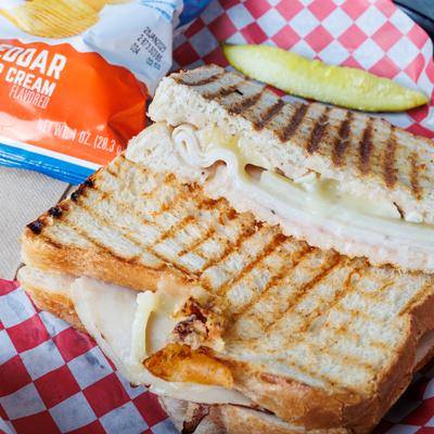 Brie & Pears hot panini served with pickle spear and chips.