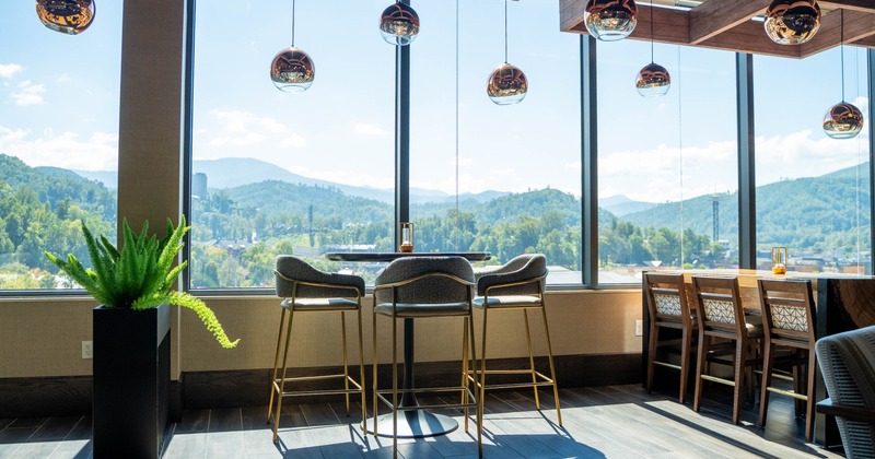A bright room with large windows, a table with bar stools