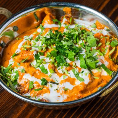 Butter chicken in creamy tomato sauce, topped with fresh herbs.