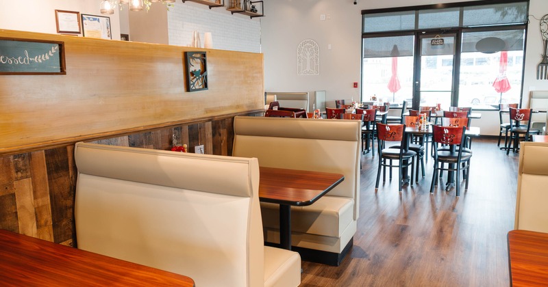 Interior of a modern restaurant with booth seating, tables and chairs, decorative lighting