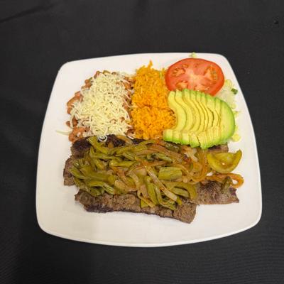 Carne asada with sides of rice, beans and sliced avocado.