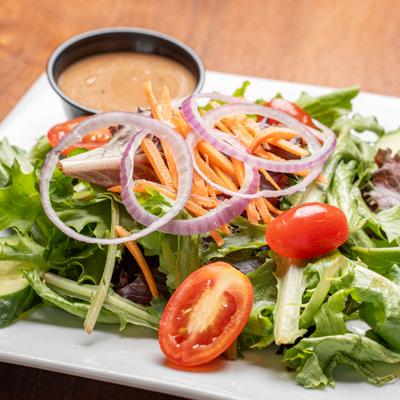 Garden salad served with a dressing on the side.