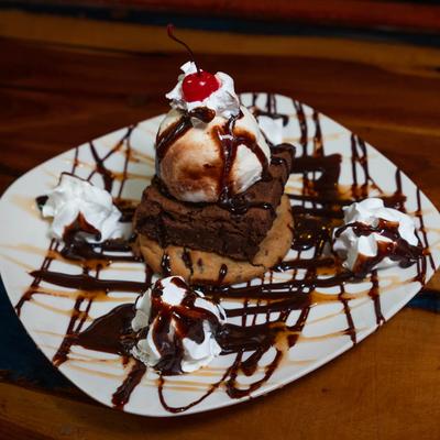 Brownie and ice cream dessert with chocolate sauce, whipped cream, and a cherry.