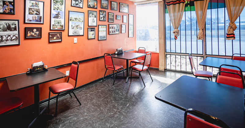 Interior, tables and chairs ready for guests, framed photos on a wall