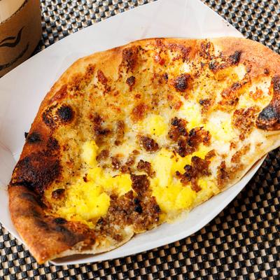 Breakfast Pizza topped with melted cheese, crumbled sausage, and scrambled egg.