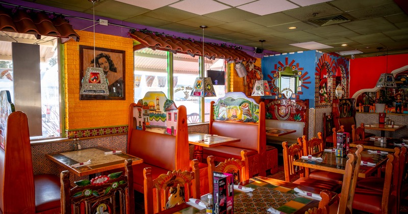 Colorful Mexican-themed restaurant interior with painted wooden booths and vibrant decor