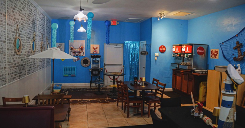 Interio, nautical-themed dining area with blue walls, hanging lanterns, and a soda fountain