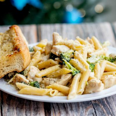 Chicken Alfredo pasta with broccoli, served with bread.