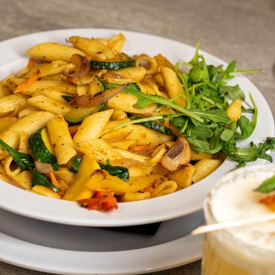 Pasta with vegetables garnished with a arugula.