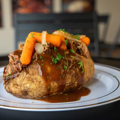 Baked potato stuffed with pot roast, gravy, and vegetables.