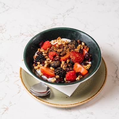 A yogurt bowl topped with a variety of fruits, nuts, and granola.