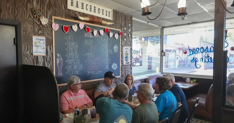 Diner area, table, people, booths, menu chalk board