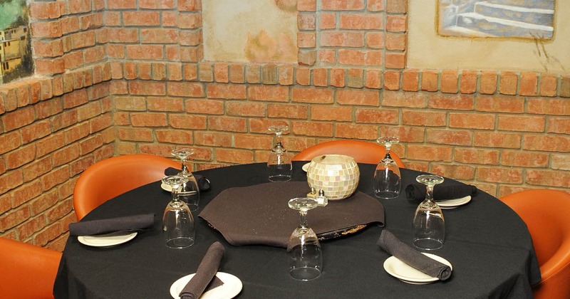 Interior, set table with black table cloth, upturned glasses, plates and rolled napkins