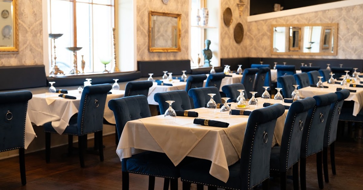 Elegant restaurant with blue velvet chairs, white tablecloths, and neatly set tables