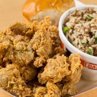 Fried chicken gizzard, served with rice, and a bread roll.