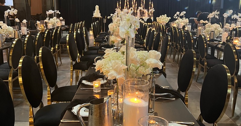 Banquet room with long tables with flowers, tableware, and candles on them