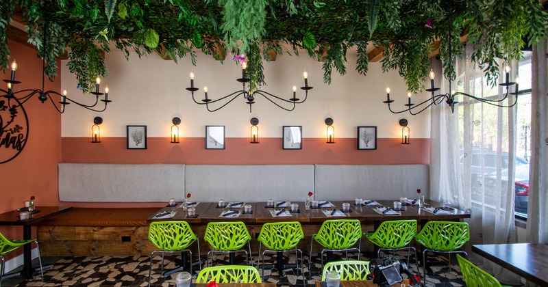 Interior, long banquette bench with tables and chairs, ready for guests, foliage ceiling decor