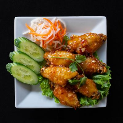 Chicken wings served with sliced cucumber and pickled vegetables.