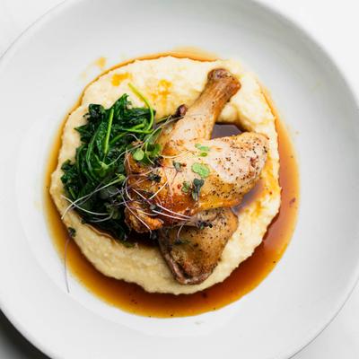 Oven Roasted Chicken with cheddar grits, spinach, and microgreens, top view.