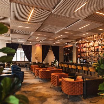 Modern restaurant lounge with a bar, seating, and decorative ceiling panels.