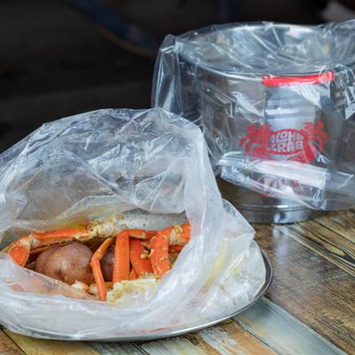Seafood boil bag with crab legs on a wooden table.