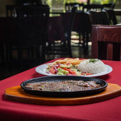Grilled steak served with fries, rice, and salad.