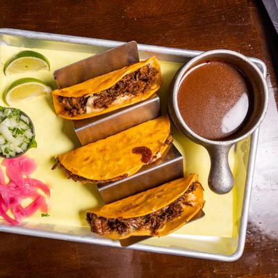 Birria tacos served with consomme dipping