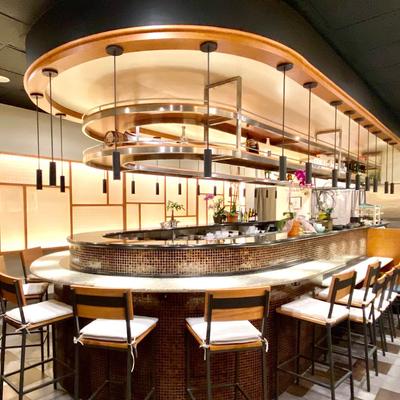 A modern bar with stools, elegant lighting, and pendant lights.