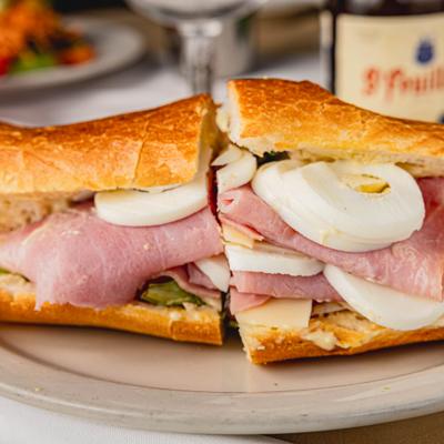 A sandwich with ham, Swiss cheese, boiled egg, lettuce, and tomato.