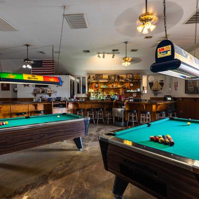 Interior with two pool tables and bar area in the background.