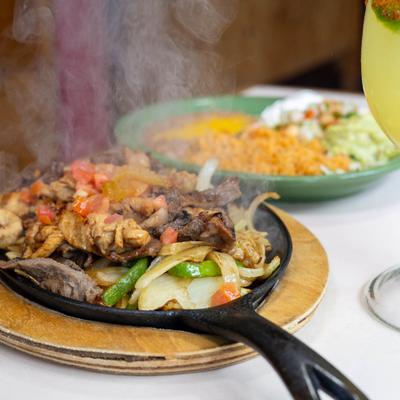 Mixed fajitas served on a sizzling skillet on a restaurant table.