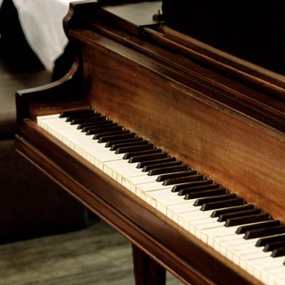 Antique-style baby grand piano featuring a rich walnut wood finish.